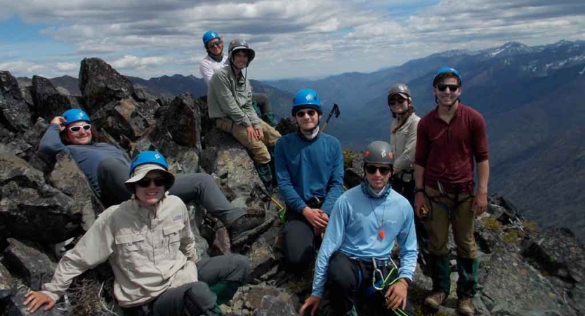a group of people wearing mountaineering gear pose for a photo on an outward bound course